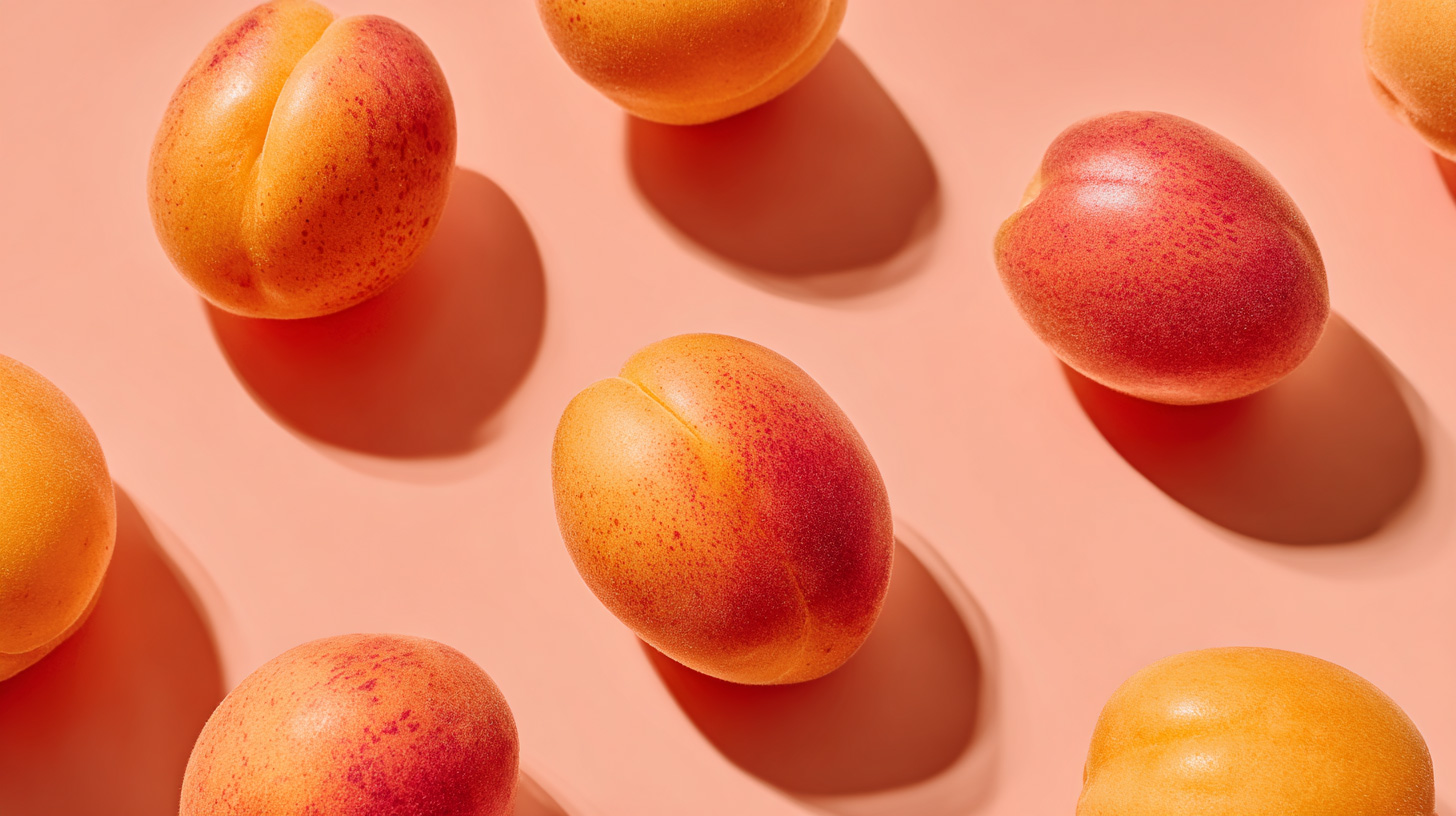 Free stock photo of fresh apricots casting soft shadows on a pastel salmon background, shot from top view