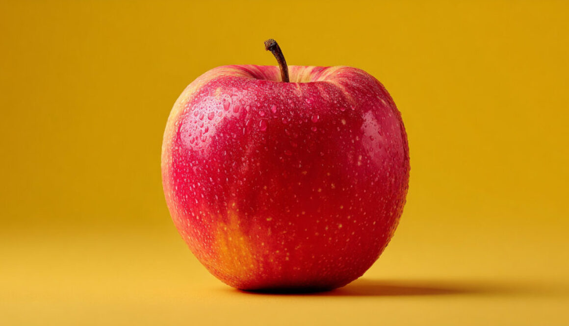 Red apple with water droplets on yellow pastel background in 16:9 format