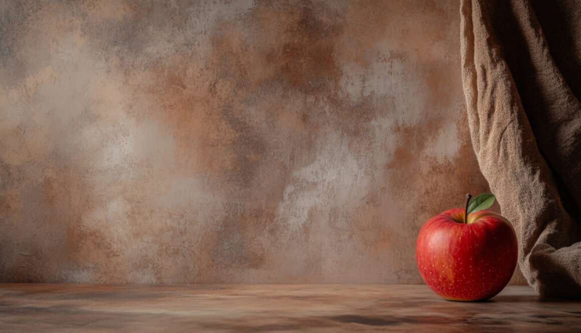 Red apple with leaf on rustic brown background and linen drape in 16:9 format
