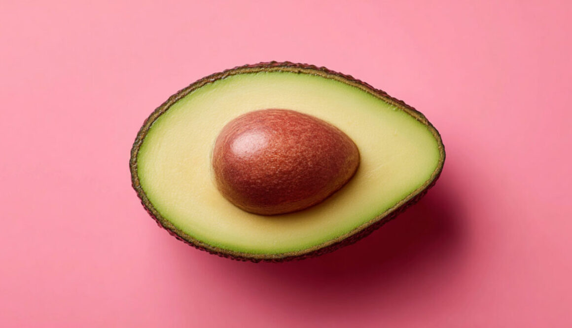 Top view of half avocado with seed on strawberry pink background in 16:9 format
