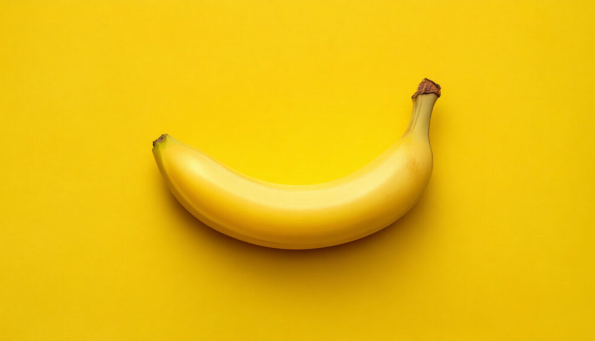 Centered ripe banana on vibrant yellow background in 16:9 format