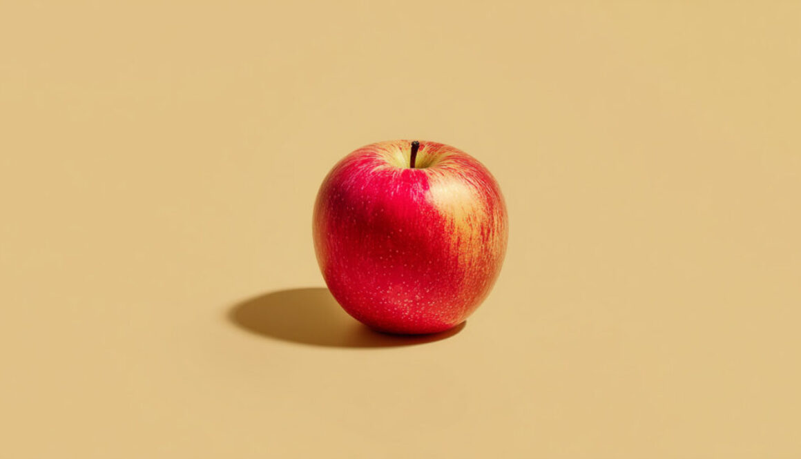 Whole red apple centered on a warm beige pastel background, free 16:9 stock photo