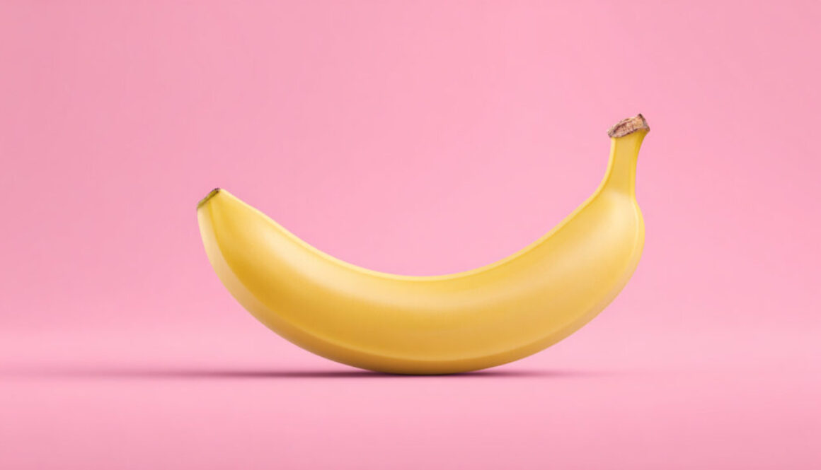 Centered ripe banana on strawberry pink background in 16:9 format