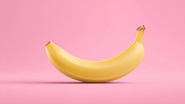 Centered ripe banana on strawberry pink background in 16:9 format