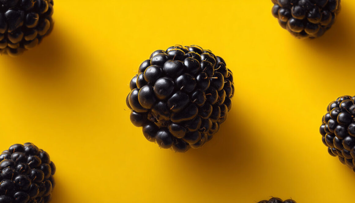 Close-up of a ripe blackberry on vivid yellow background in 16:9 format