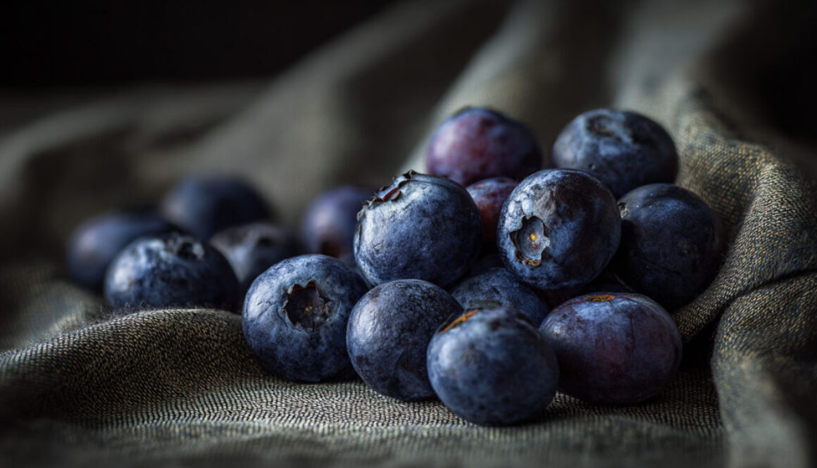 Rustic still life of ripe blueberries on textured dark fabric in 16:9 format