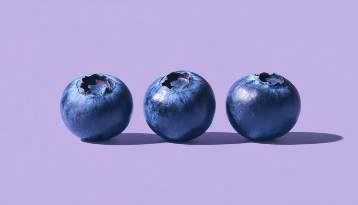 Three blueberries on soft purple background in 16:9 format