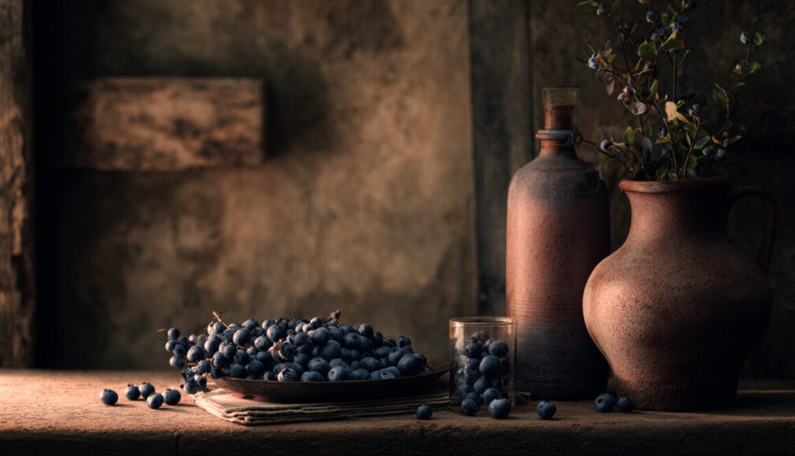 Rustic still life of fresh blueberries with clay vases on warm brown background in 16:9 format