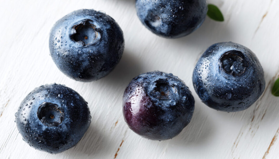 Fresh blueberries with water droplets on white wooden background in 16:9 format