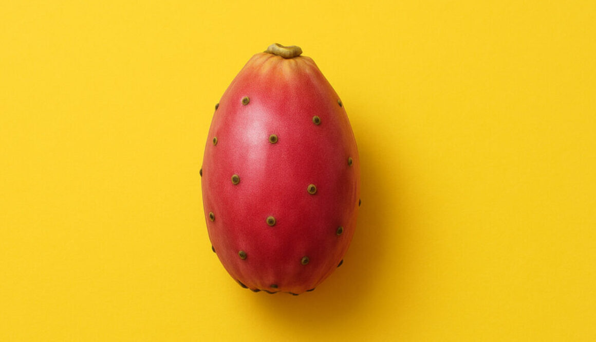 Red cactus fruit centered on bright yellow background in 16:9 format