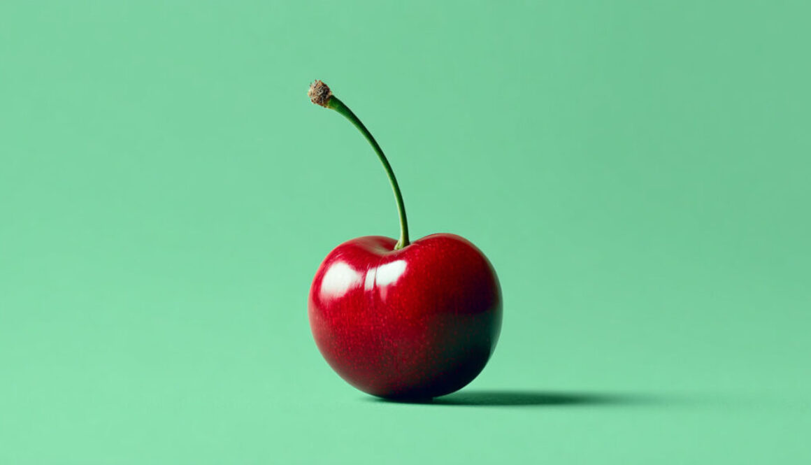 Single ripe red cherry centered on solid green background in 16:9 format