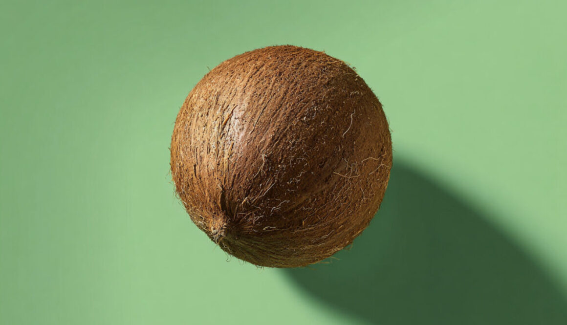 Whole coconut centered on green solid background with shadow in 16:9 format