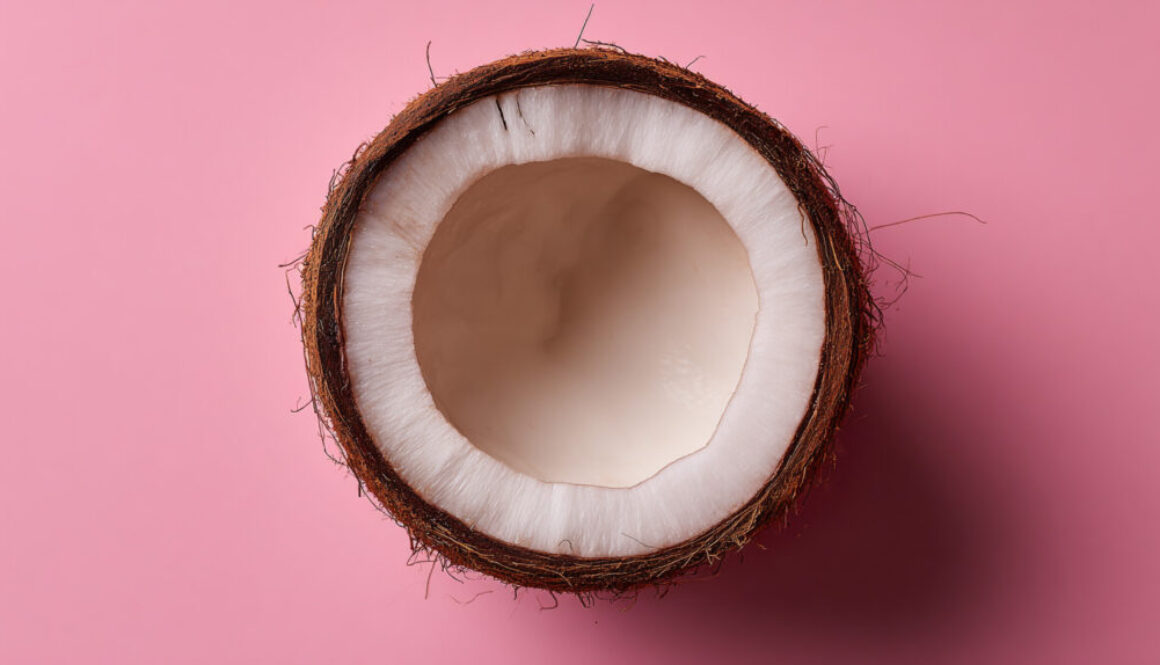 Half coconut with white flesh on pink solid background in 16:9 format