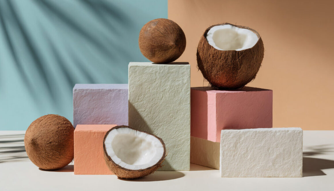 Modern still life with whole and halved coconuts on colorful pastel blocks in 16:9 format