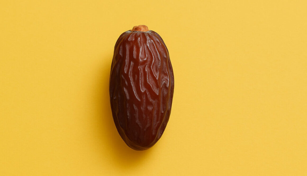 Minimal shot of a single date fruit on bright yellow background in 16:9 format