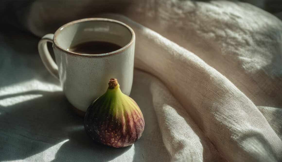 Fresh fig placed next to a ceramic coffee cup on soft linen cloth with natural light in 16:9 format