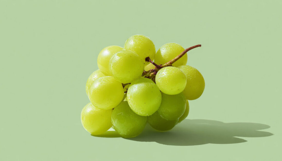 Fresh green grape cluster centered on light green solid background in 16:9 format