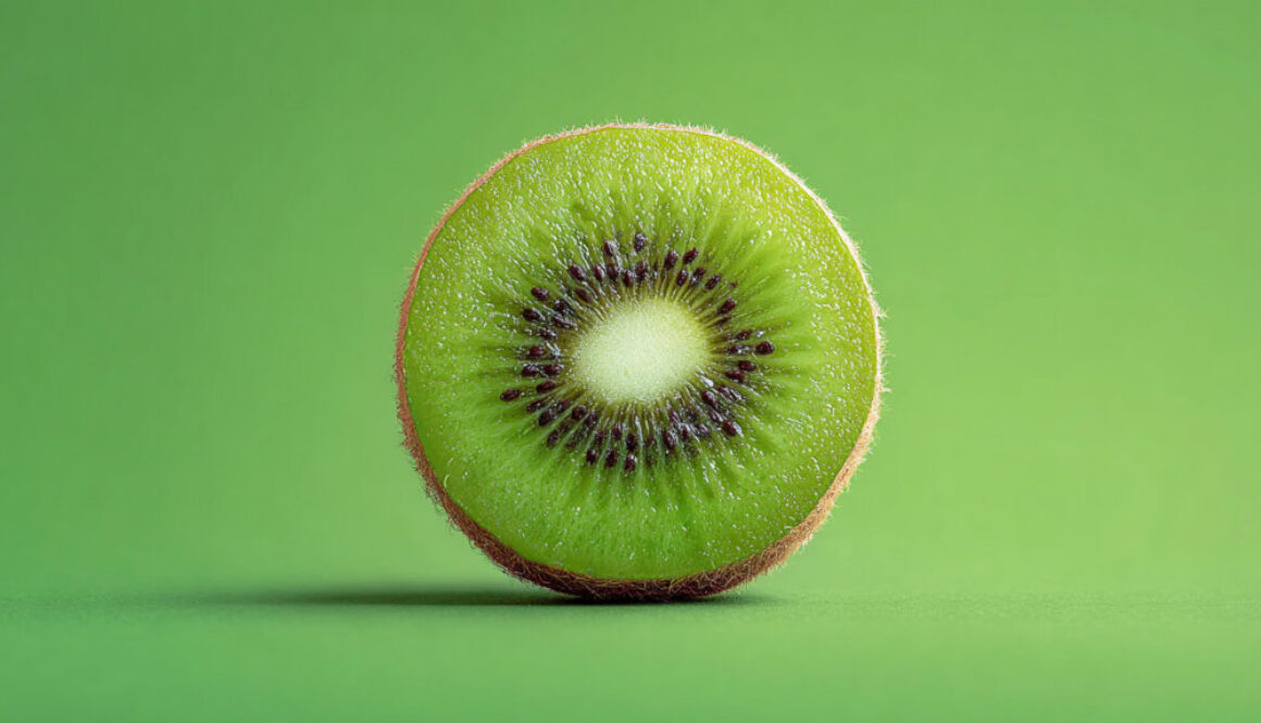 Half slice of fresh kiwi centered on solid green background