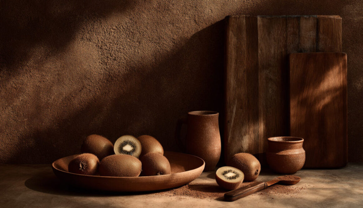 Rustic still life with fresh kiwi in ceramic bowl on warm brown background