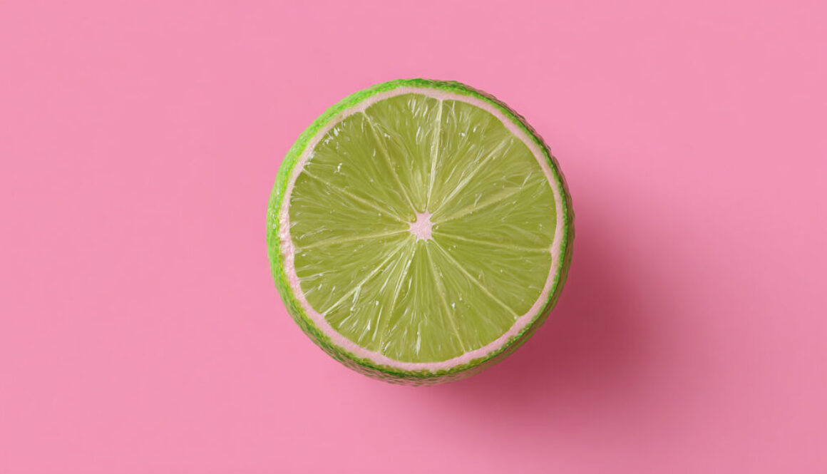 Top view of halved lime on pastel pink background in 16:9 format